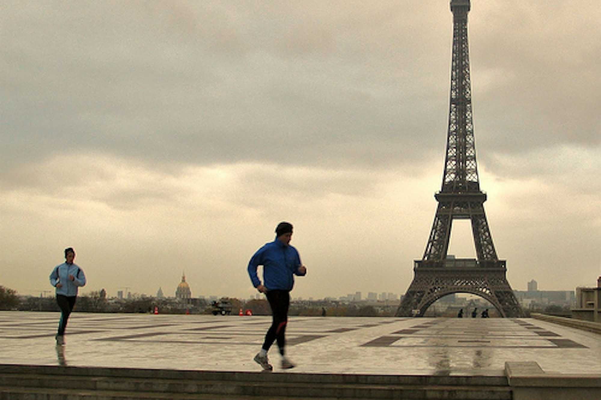 Pareja corriendo con la Torre Eiffel de fondo al atardecer